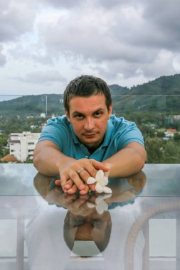 2011.05.10, Phuket, Tayland. Phuket doğanın backgrounf üzerinde cam masa nın yanında oturan genç bir adamın portresi.