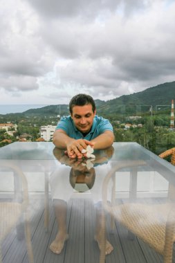 2011.05.10, Phuket, Tayland. Phuket doğanın backgrounf üzerinde cam masa nın yanında oturan genç bir adamın portresi.