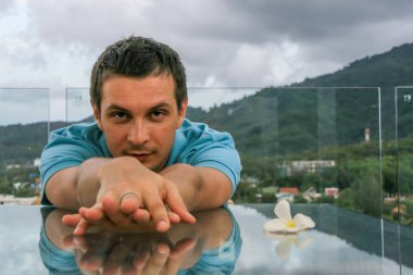 2011.05.10, Phuket, Tayland. Phuket doğanın backgrounf üzerinde cam masa nın yanında oturan genç bir adamın portresi.