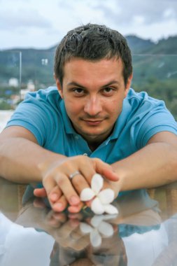 2011.05.10, Phuket, Tayland. Phuket doğanın backgrounf üzerinde cam masa nın yanında oturan genç bir adamın portresi.