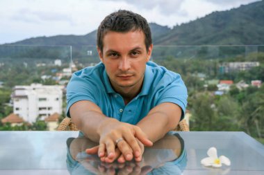 2011.05.10, Phuket, Tayland. Phuket doğanın backgrounf üzerinde cam masa nın yanında oturan genç bir adamın portresi.