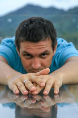 2011.05.10, Phuket, Tayland. Phuket doğanın backgrounf üzerinde cam masa nın yanında oturan genç bir adamın portresi.