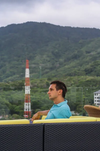 2011.05.10, Phuket, Tayland. Otelin çatısındaki kanepede oturan genç bir adam. Kameraya bakan bir adam. Phuket Turizm.