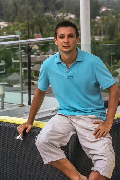 2011.05.10, Phuket, Tayland. Otelin çatısındaki kanepede oturan genç bir adam. Kameraya bakan bir adam. Phuket Turizm.
