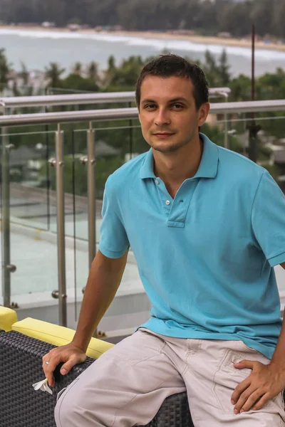 2011.05.10, Phuket, Tayland. Otelin çatısındaki kanepede oturan genç bir adam. Kameraya bakan bir adam. Phuket Turizm.