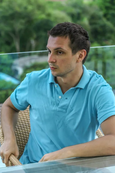 2011.05.10, Phuket, Tayland. Otelin çatısında cam çitlerin yanında duran genç bir adam. Phuket plajının arka planında kameraya bakan bir adam.