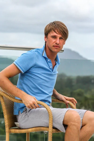 2011.05.10, Phuket, Tayland. Köyün arka planında otelin çatısındaki koltukta oturan genç bir adam. Phuket Turizm.