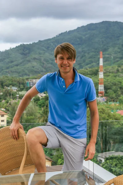 2011.05.10, Phuket, Tayland. Otelin çatısında cam çitlerin yanında duran genç bir adam. Kameraya bakan bir adam. Phuket Turizm.