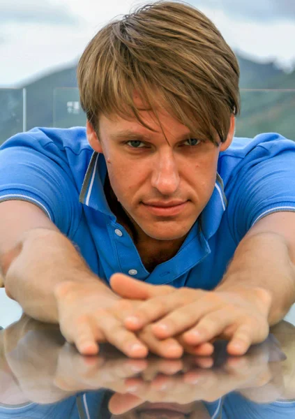 2011.05.10, Phuket, Tayland. Bir masada oturan ve önünde ellerini uzatan genç bir adamın portresi. Asya'da seyahat.