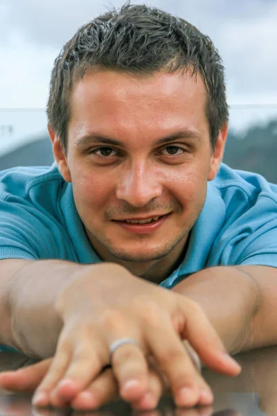 2011.05.10, Phuket, Tayland. Phuket doğanın backgrounf üzerinde cam masa nın yanında oturan genç bir adamın portresi.