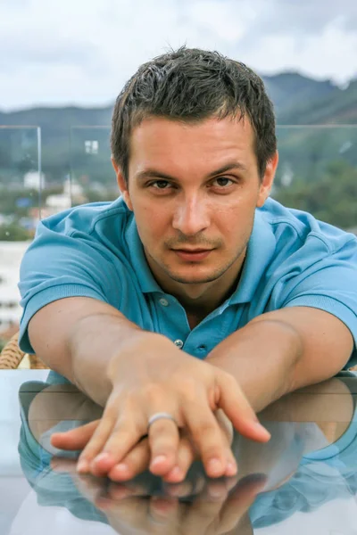 2011.05.10, Phuket, Tayland. Phuket doğanın backgrounf üzerinde cam masa nın yanında oturan genç bir adamın portresi.