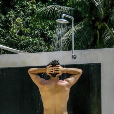 2011.05.11, Phuket, Tayland. genç adam dairenin çatısında duş altında duruyor, arka tarafı görünümü, tahıl ve bulanıklık etkisi. Asya'da seyahat.