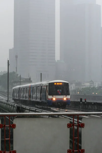 2011 交通系统 下雨天摩天大楼背景的地铁列车 强雨天气 模糊和谷物效果 — 图库照片