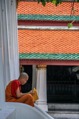 2011.05.16, Bangkok, Tayland. Genç Budist keşiş, Büyük Saray tapınağının merdivenlerinde dinleniyor. Asya 'nın antik mimarisi. Bangkok manzarası.