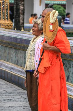 2011.05.16, Bangkok, Tayland. Budist keşiş ve turist eski tapınağın arka planında kameraya poz veriyor, bulanıklık ve tahıl etkisi.