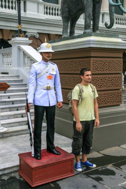 2011.05.16, Bangkok, Tayland. Bangkok manzarası. Beyaz elbiseli şenlikli muhafız ve yanında duran Avrupalı turist.