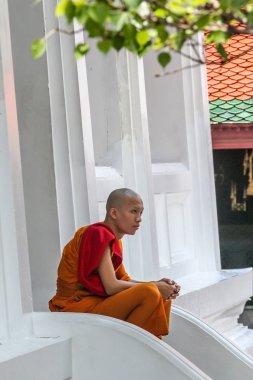 2011.05.16, Bangkok, Tayland. Genç Budist keşiş, Büyük Saray tapınağının merdivenlerinde dinleniyor. Asya 'nın antik mimarisi. Bangkok manzarası.