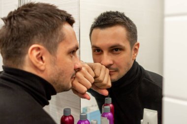 Siyah balıkçı yaka giyen ve aynaya bakan kısa saçlı genç bir adamın portresi. Aynaya bakan genç bir adamın yansıması..