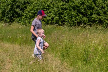 24.06.2020, Maloyaroslavets. - Rusya. İki çocuk kelebek yakalayacak. Küçük kardeşler tarlada yürüyor..