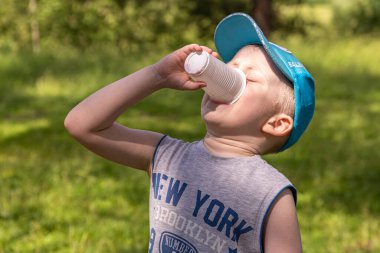 24.06.2020, Maloyaroslavets. - Rusya. Plastik bardaktan meyve yiyen küçük bir çocuk. Açık havada akşam yemeği.