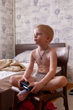 26.06.2020, Maloyaroslavets, Rusya. Küçük beyaz bir çocuk sandalyede oturur ve evde oyun oynar. Çocuklar evde dinleniyor..