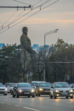 25.11.2012, Krasnodar, Rusya. Şehrin merkez caddelerinden birinde farları yanan arabalar tarihi bir anıtın arka planına karşı.