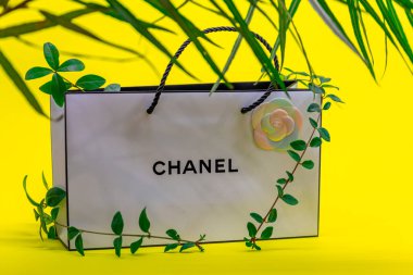 08.10.2020, Moskova, Rusya. Beyaz Chanel çanta, tırmanma bitkisi ve sarı arka planda palmiye yaprağı gölgeleri..