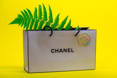 08.10.2020, Moskova, Rusya. Sarı arka planda beyaz Chanel çanta ve eğreltiotu yaprakları.