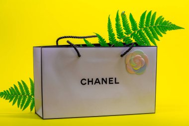 08.10.2020, Moskova, Rusya. Sarı arka planda beyaz Chanel çanta ve eğreltiotu yaprakları.