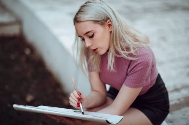 Park içinde genç güzel kız ressam çizmek