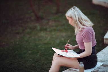 Park içinde genç güzel kız ressam çizmek
