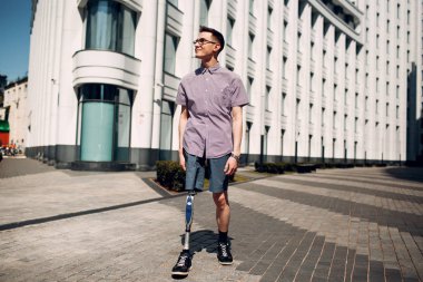 Taban protezi ile Engelli genç adam cadde boyunca yürür.