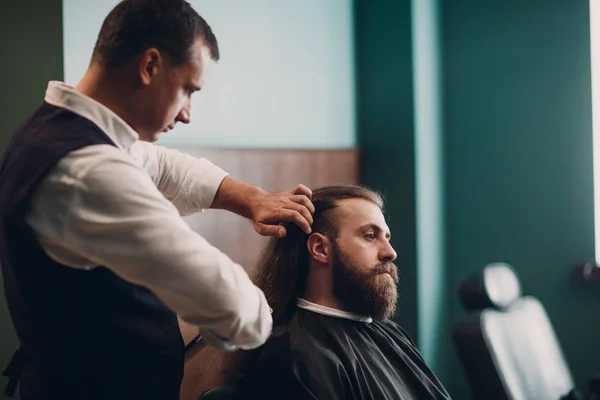 Barbershop with wooden interior. Bearded model man and barber.