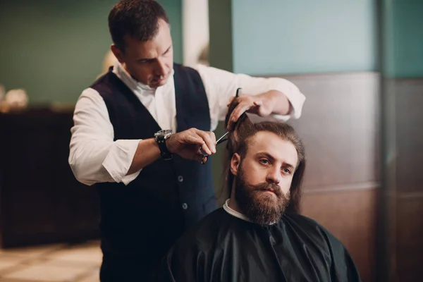 Barbershop with wooden interior. Bearded model man and barber.