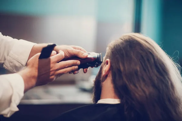 Hairdresser make hairstyle. Bearded model man and barber hand with razor trimmer and comb.