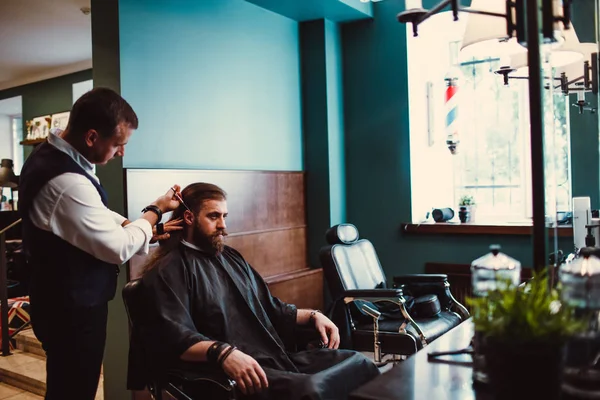 Barbershop with wooden interior. Bearded model man and barber