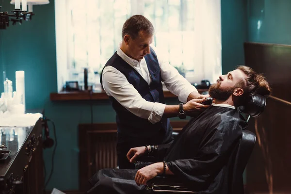Barbershop with wooden interior. Bearded model man and barber