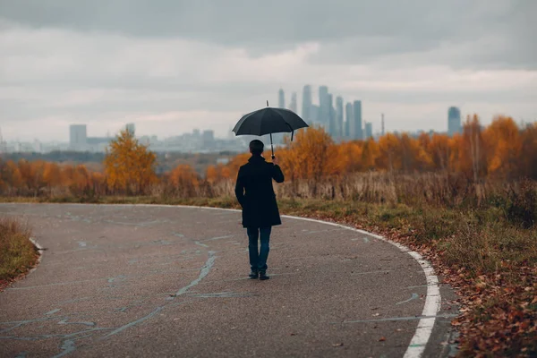 Jonge Man Zwarte Jas Lopen Naar Stad Met Wolkenkrabbers Regen — Stockfoto