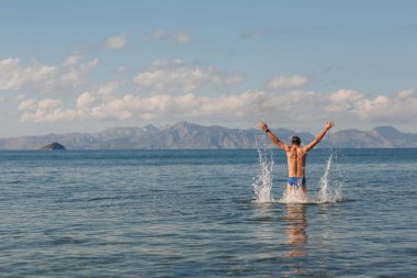 Genç bir adam elleriyle dağlar zemin denizle kadar atlama