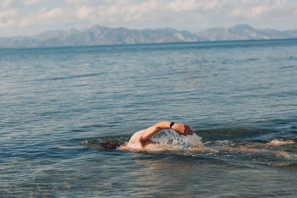 Seorang Pemuda Berenang Laut Terhadap Latar Belakang Pegunungan — Stok Foto