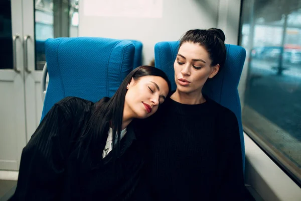 Two girlfriends sleeping during trip by railway train