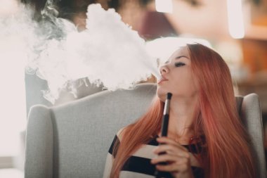 Genç güzel kadın sigara ve exhales nargile. Duman shisha nargile kavramı.