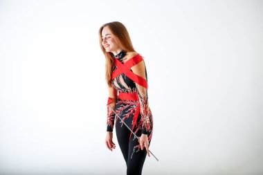 Ritmik jimnastik. Beyaz arka plan üzerinde kırmızı kurdele ile genç jimnastikçi kız