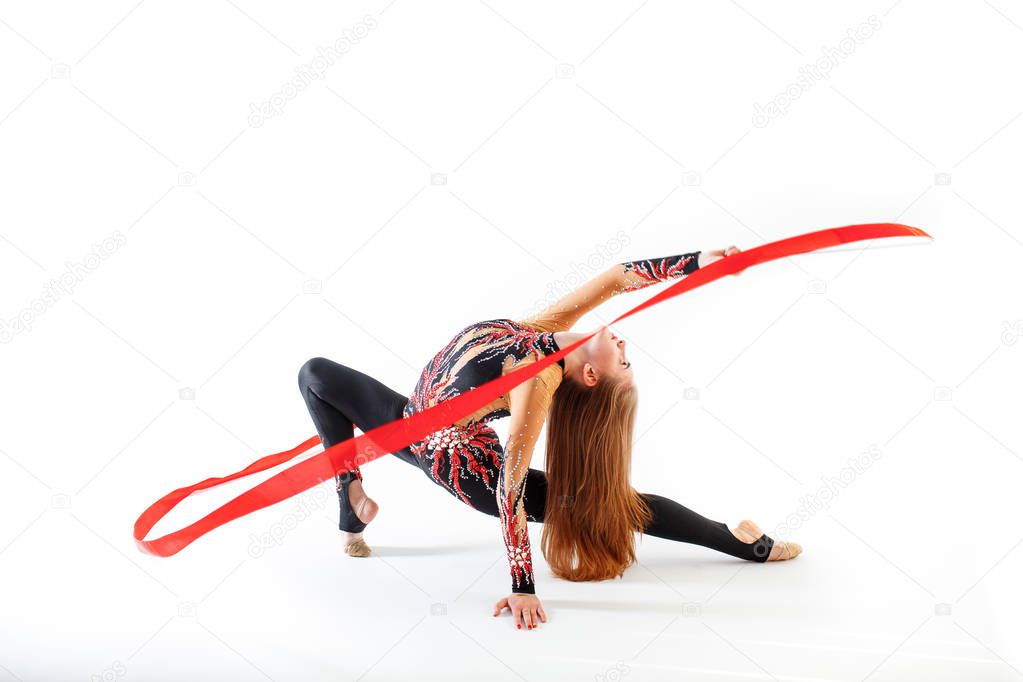 Rhythmic gymnastics. Young gymnast girl with red ribbon on white background