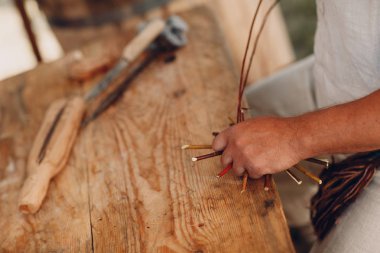 Usta adam bir sepet dalları örüyor.