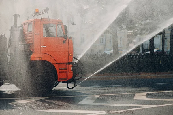 Watering machine pours water on the road