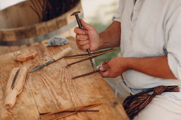 Usta adam bir sepet dalları örüyor.
