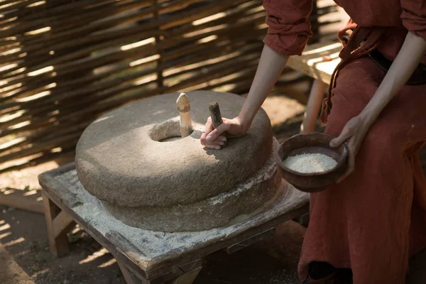 Woman grinds wheat and makes flour on millstone