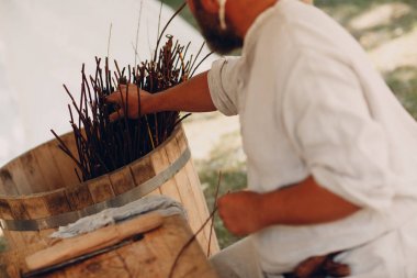 Usta adam bir sepet dalları örüyor.