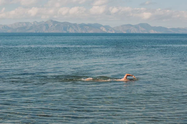 Seorang Pemuda Berenang Laut Terhadap Latar Belakang Pegunungan — Stok Foto
